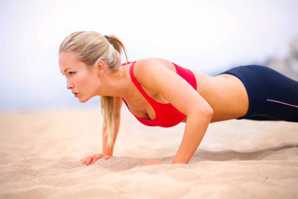 Woman doing pushups on beach